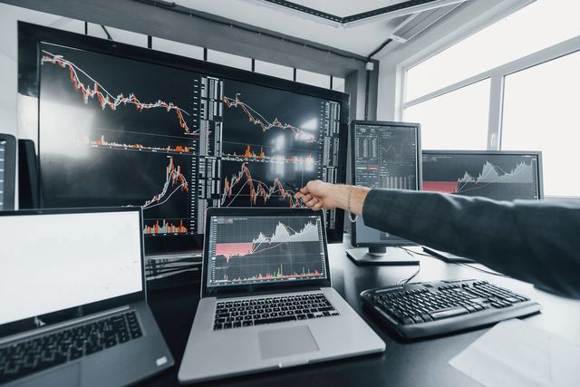 Un analista indica dei grafici su più monitor