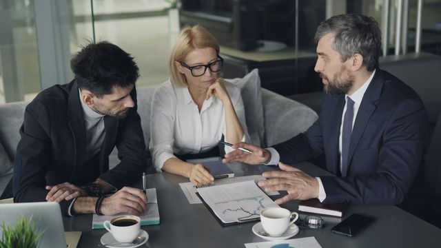 Una persona indica un grafico stampato mentre le altre due seguono